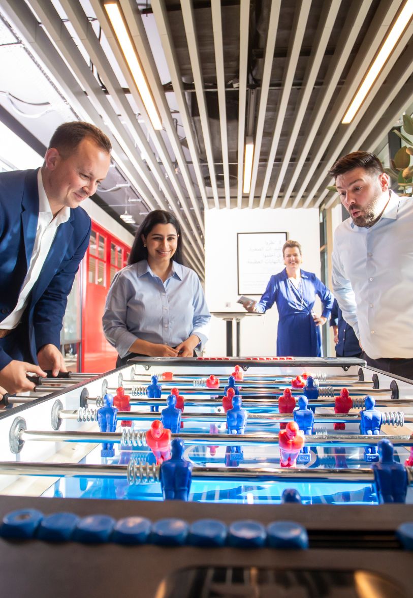 Ignite team building activity with employees playing table football together.